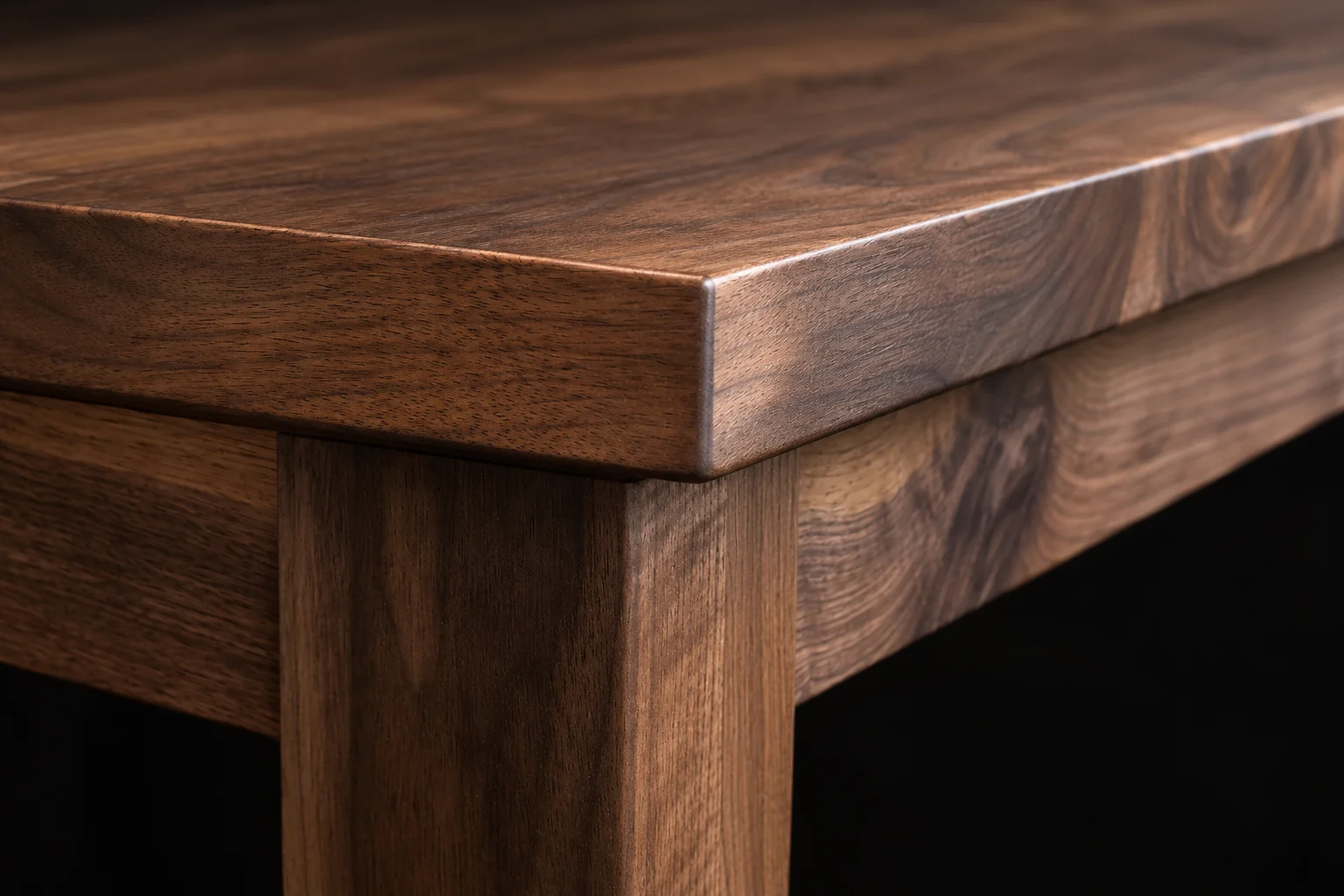 Close view of a walnut tabletop edge, apron, and straight leg